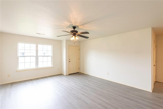 unfurnished room with baseboards, a ceiling fan, light wood finished floors, and visible vents