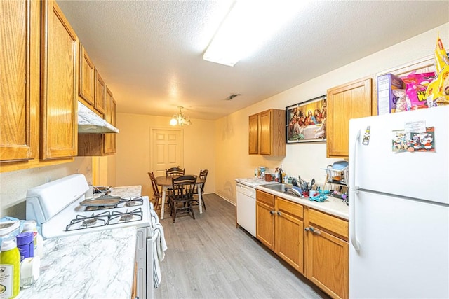 kitchen with white appliances, light countertops, under cabinet range hood, a sink, and light wood-style flooring
