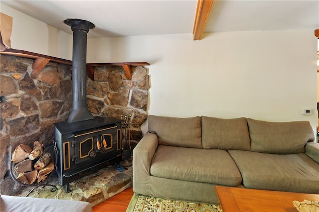 living room featuring beam ceiling, wood finished floors, and a wood stove
