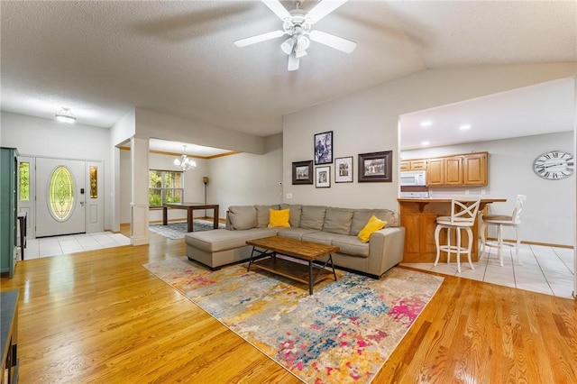 2 Saxilby Ln, Bella Vista, AR 72715 - living area with light wood-type flooring, baseboards, ceiling fan with notable chandelier, and vaulted ceiling
