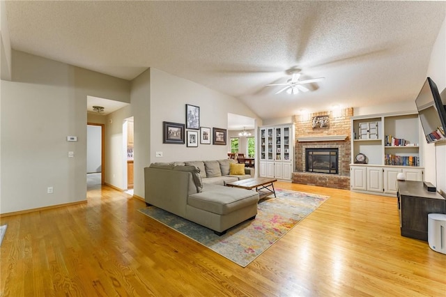 2 Saxilby Ln, Bella Vista, AR 72715 - living room with ceiling fan, a brick fireplace, a textured ceiling, light wood-style flooring, and lofted ceiling