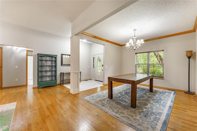2 Saxilby Ln, Bella Vista, AR 72715 - unfurnished dining area with a notable chandelier, light wood finished floors, a textured ceiling, decorative columns, and ornamental molding