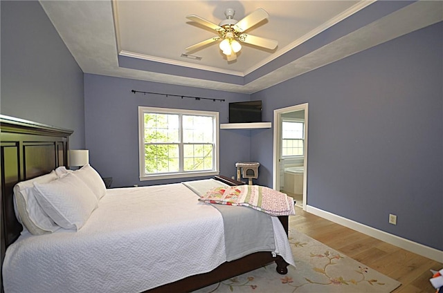 bedroom featuring a raised ceiling, baseboards, wood finished floors, visible vents, and ornamental molding