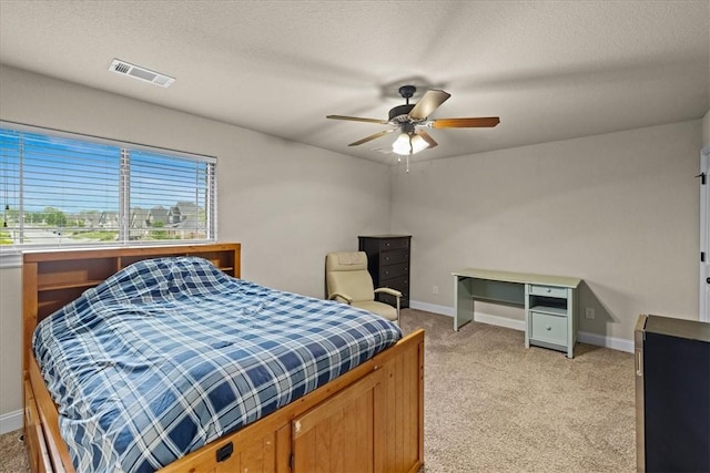 bedroom with ceiling fan, light carpet, a textured ceiling, baseboards, and visible vents