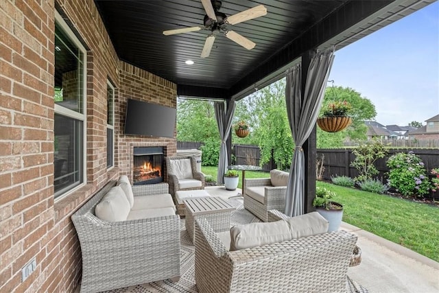view of patio / terrace featuring a fenced backyard, a ceiling fan, and an outdoor living space with a fireplace