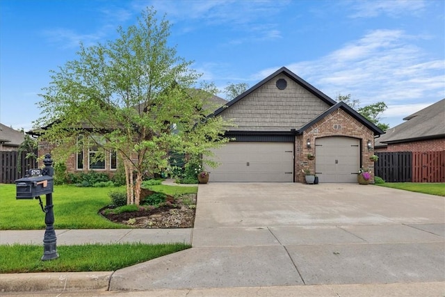 craftsman inspired home featuring driveway, a front yard, brick siding, fence, and an attached garage