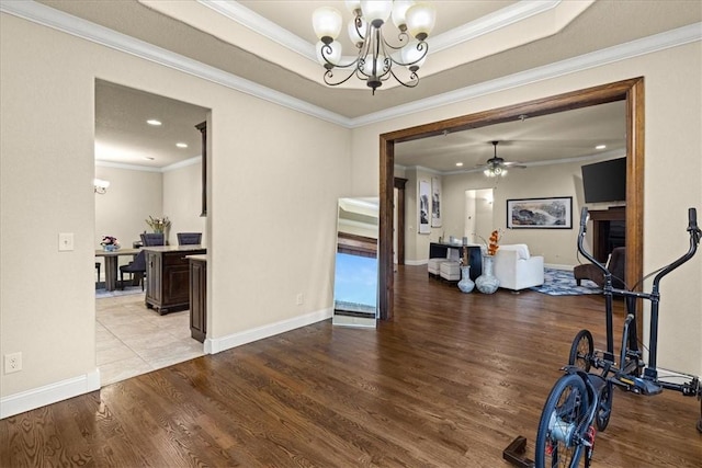 dining room with crown molding, a raised ceiling, ceiling fan with notable chandelier, recessed lighting, and wood finished floors