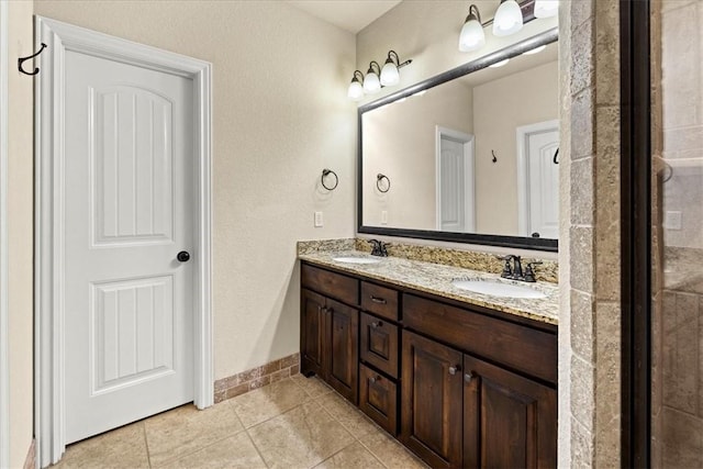 bathroom featuring tile patterned flooring, a sink, baseboards, and double vanity