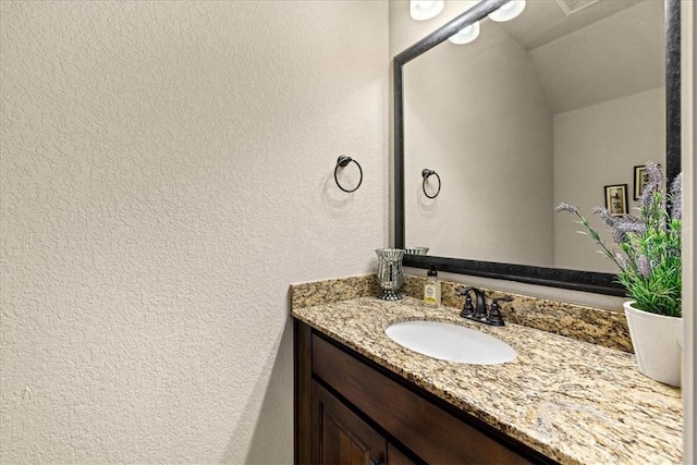 bathroom with a textured wall and vanity