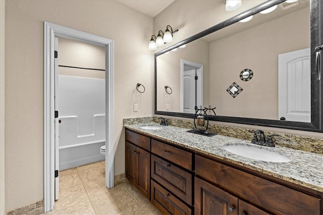 full bath with a sink, tile patterned floors, toilet, and double vanity