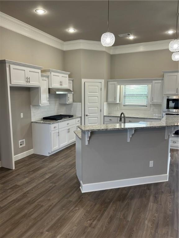 kitchen with crown molding, a breakfast bar area, and gas stovetop