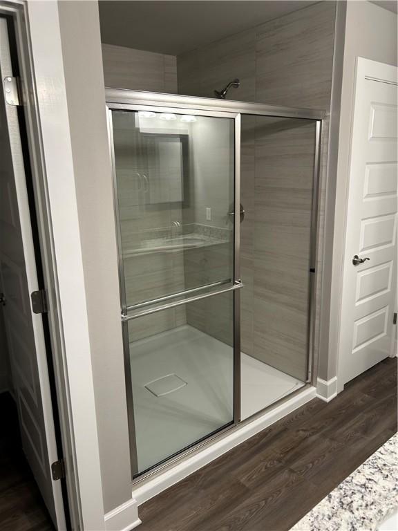 full bathroom featuring wood finished floors, baseboards, and a stall shower