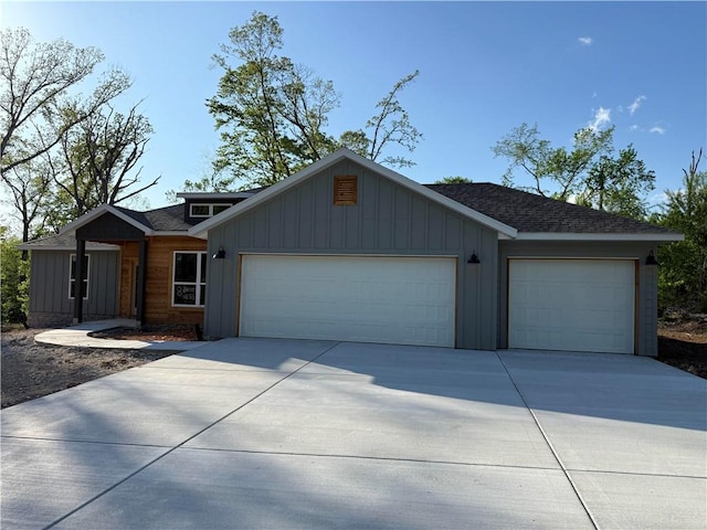 view of front facade featuring an attached garage, board and batten siding, roof with shingles, and driveway