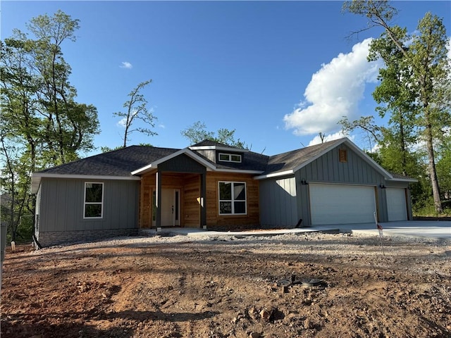 view of front of home featuring an attached garage, a shingled roof, board and batten siding, and driveway