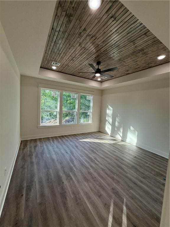 interior space featuring a ceiling fan, baseboards, dark wood-type flooring, a tray ceiling, and visible vents
