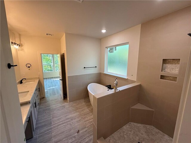 bathroom with visible vents, double vanity, a freestanding tub, a sink, and a tile shower
