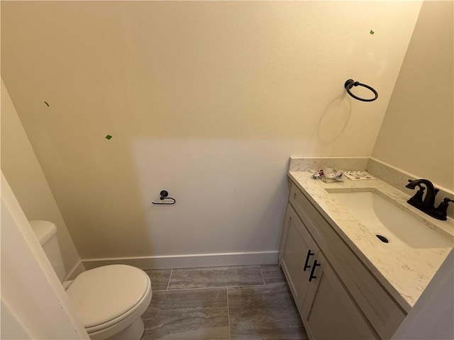 bathroom featuring vanity, baseboards, and toilet