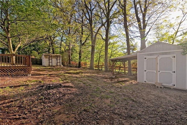 view of yard featuring an outdoor structure, a wooden deck, a storage shed, and fence