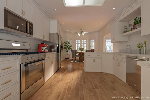 kitchen with stainless steel appliances, white cabinetry, a peninsula, and light wood-type flooring
