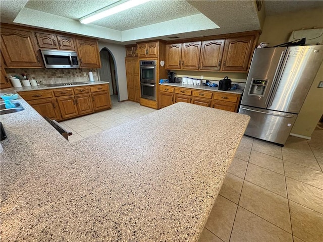 60 N Redwood Cir, Sallisaw, OK 74955 - kitchen with appliances with stainless steel finishes, light countertops, arched walkways, a textured ceiling, and light tile patterned floors