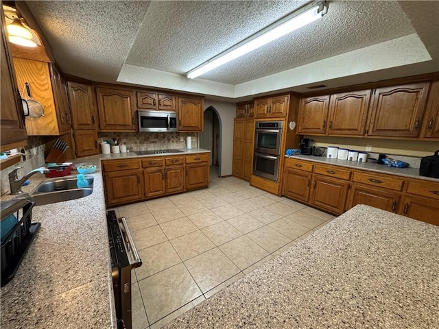 60 N Redwood Cir, Sallisaw, OK 74955 - kitchen featuring appliances with stainless steel finishes, a sink, arched walkways, a textured ceiling, and a tray ceiling