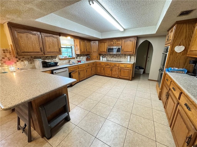 60 N Redwood Cir, Sallisaw, OK 74955 - kitchen featuring brown cabinetry, visible vents, arched walkways, light countertops, and stainless steel appliances