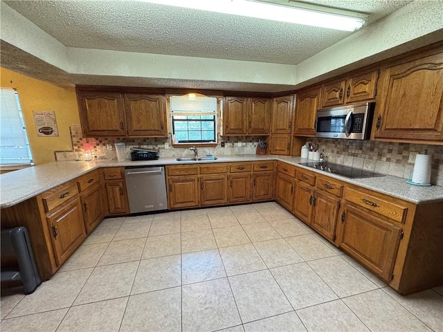 60 N Redwood Cir, Sallisaw, OK 74955 - kitchen with a peninsula, appliances with stainless steel finishes, brown cabinetry, and a sink