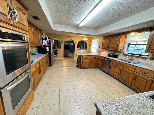 60 N Redwood Cir, Sallisaw, OK 74955 - kitchen featuring a peninsula, a textured ceiling, arched walkways, a sink, and stainless steel appliances