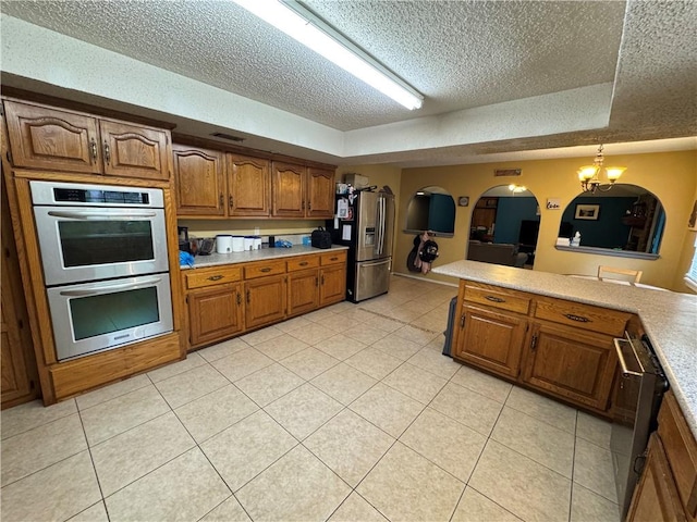 60 N Redwood Cir, Sallisaw, OK 74955 - kitchen featuring brown cabinets, light countertops, a textured ceiling, stainless steel appliances, and light tile patterned floors