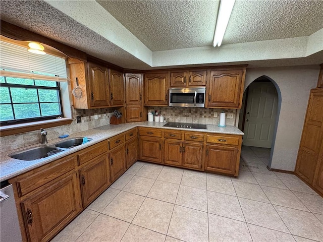 60 N Redwood Cir, Sallisaw, OK 74955 - kitchen with a sink, black electric cooktop, brown cabinetry, stainless steel microwave, and backsplash