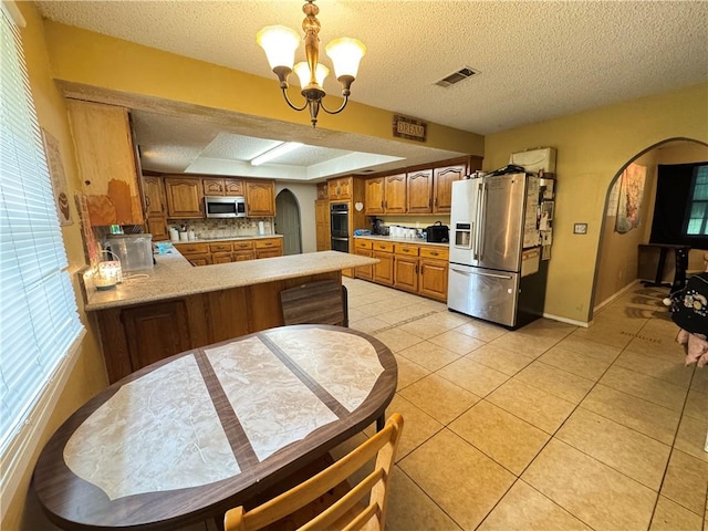 60 N Redwood Cir, Sallisaw, OK 74955 - kitchen featuring brown cabinets, appliances with stainless steel finishes, light countertops, arched walkways, and visible vents