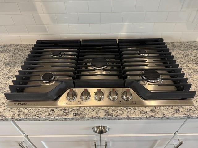 details featuring light stone counters and stainless steel gas cooktop