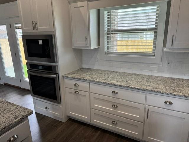 kitchen with tasteful backsplash, dark wood finished floors, white cabinetry, and oven