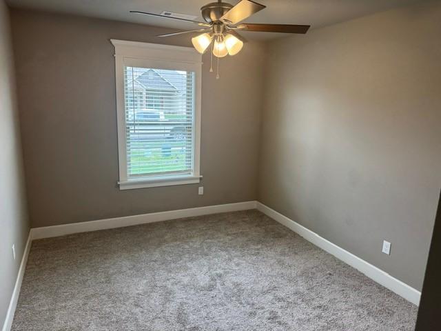 empty room with carpet flooring, a ceiling fan, and baseboards
