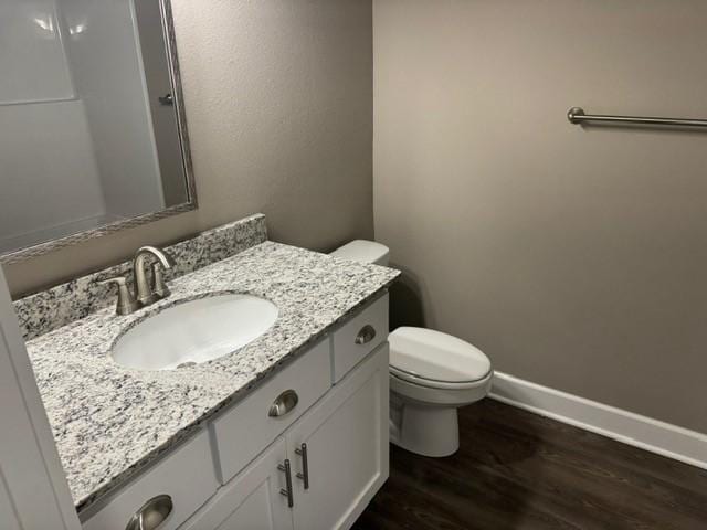 bathroom with vanity, baseboards, wood finished floors, and toilet