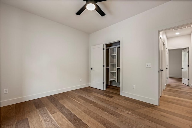 unfurnished bedroom featuring a walk in closet, a ceiling fan, visible vents, light wood-type flooring, and baseboards