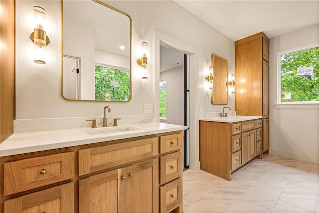 bathroom featuring a sink, baseboards, two vanities, and marble finish floor