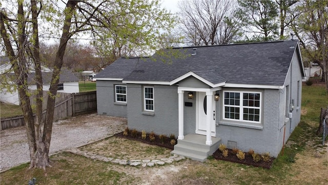 bungalow-style home with crawl space, brick siding, fence, and roof with shingles