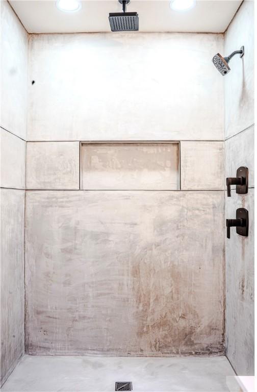 full bathroom with a tile shower and concrete floors