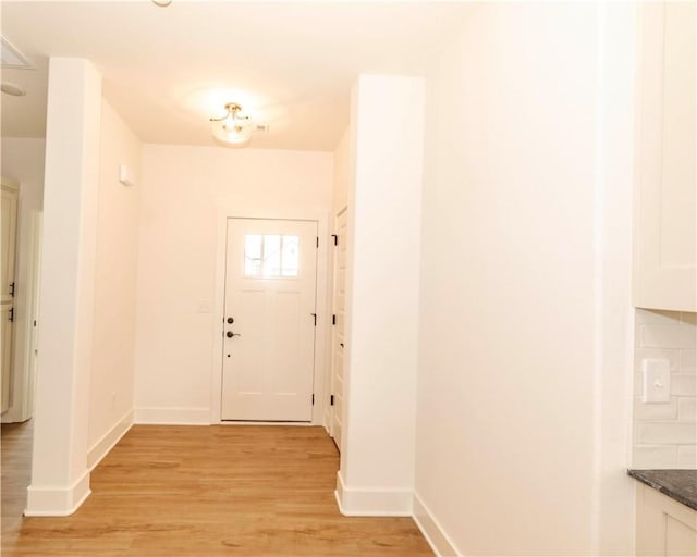 doorway to outside featuring baseboards and light wood-type flooring