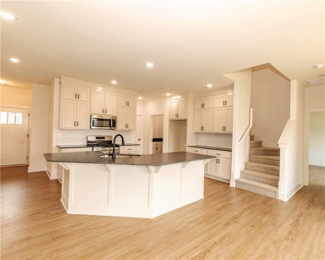 kitchen with a sink, appliances with stainless steel finishes, light wood finished floors, and recessed lighting