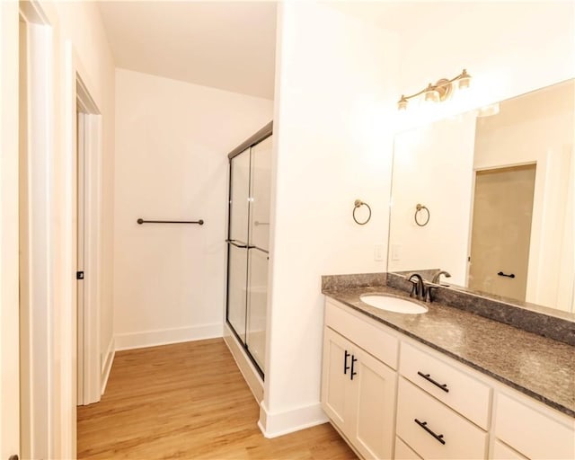 full bathroom featuring vanity, baseboards, a shower stall, and wood finished floors