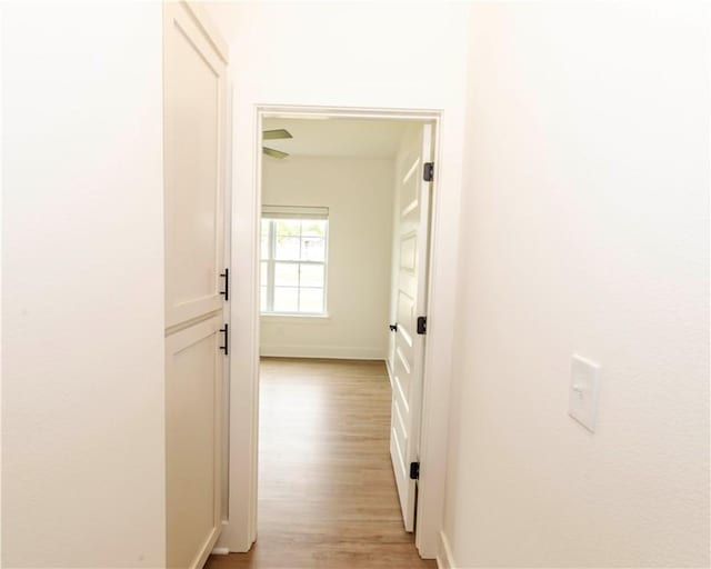 corridor with baseboards and light wood-style flooring