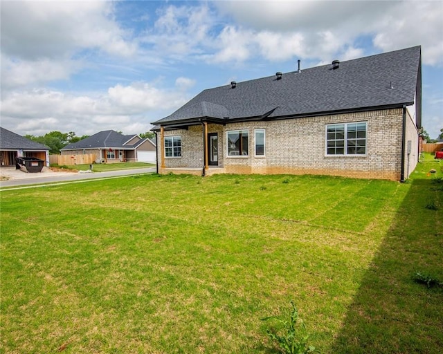 rear view of property featuring roof with shingles, a lawn, and brick siding