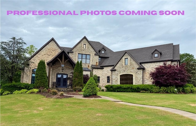 view of front facade with brick siding, french doors, stone siding, and a front lawn