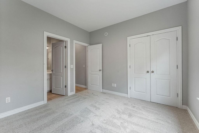 unfurnished bedroom featuring baseboards, ensuite bathroom, carpet, and a closet