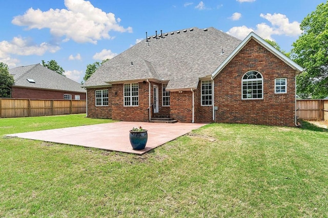 rear view of house with a lawn, brick siding, a fenced backyard, a patio, and a shingled roof