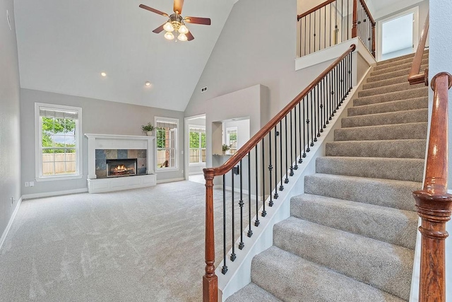 staircase with carpet flooring, a ceiling fan, high vaulted ceiling, and baseboards
