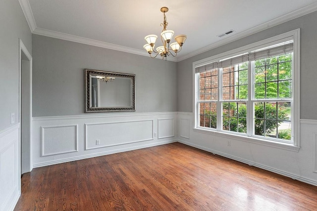 unfurnished room with crown molding, a chandelier, and a wainscoted wall