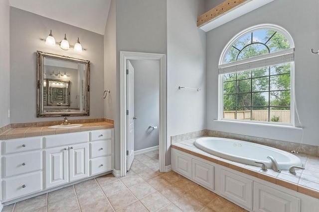 bathroom featuring vanity, lofted ceiling, baseboards, a bath, and tile patterned floors